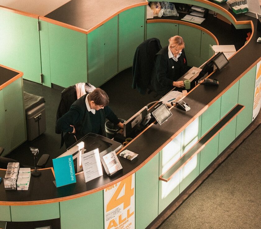 man in black jacket sitting beside brown wooden desk